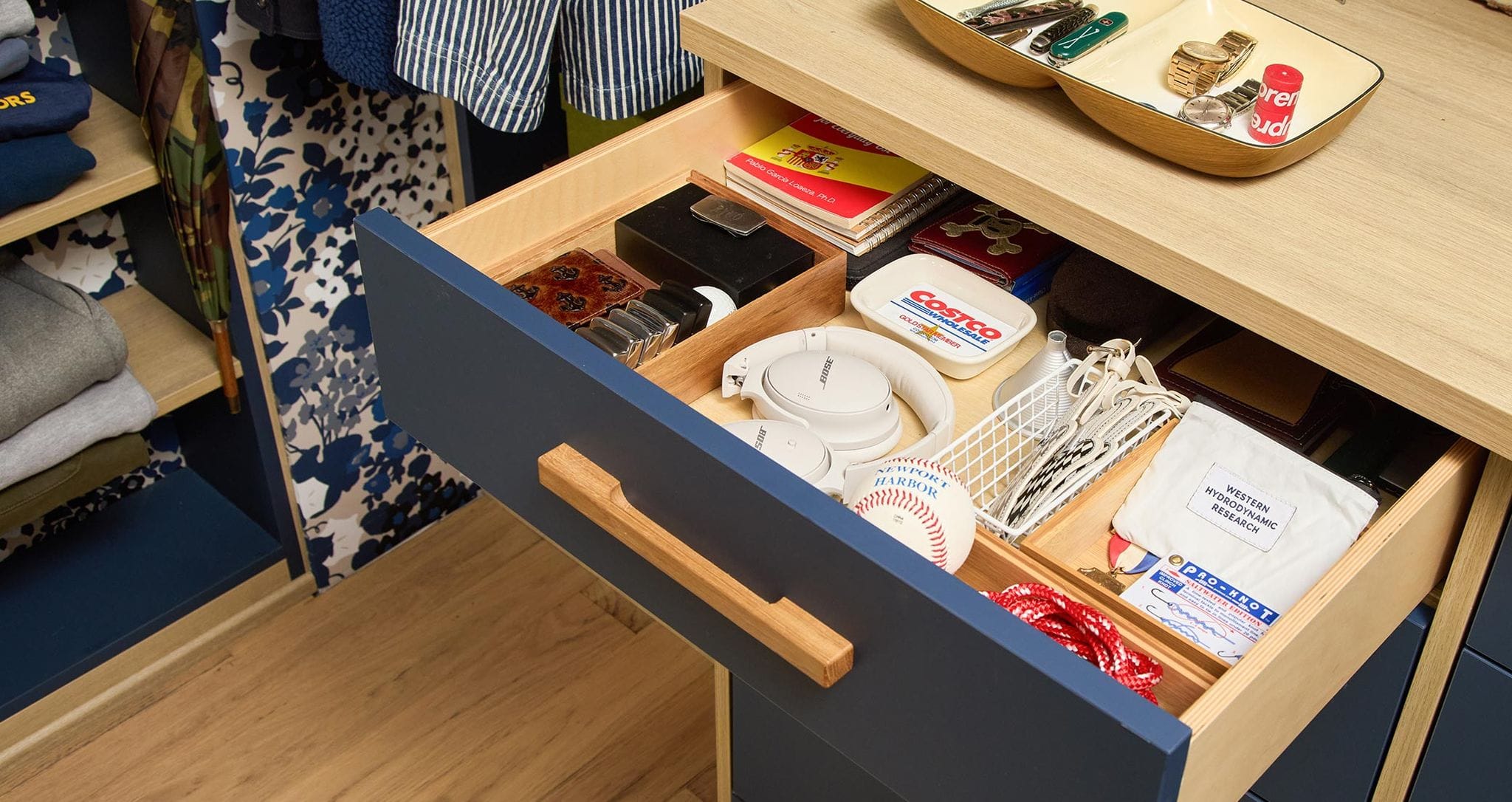 A custom closet with blue and natural wood finishes and custom drawer space by California Closets