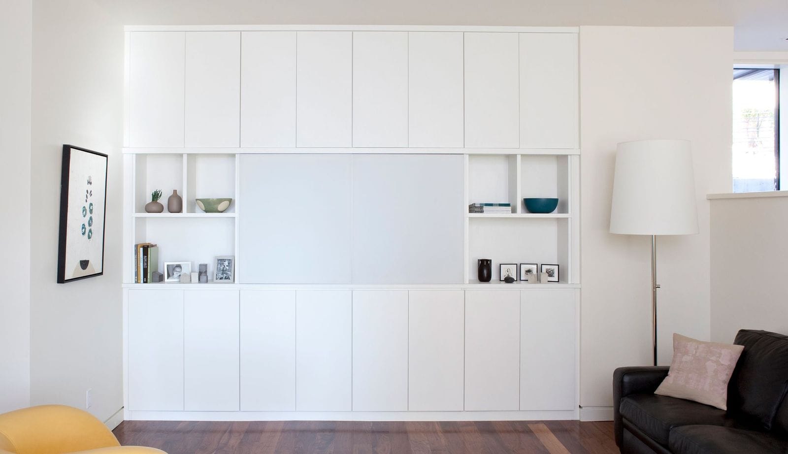 Installation of a media center with custom white finish storage cabinets created by California Closets